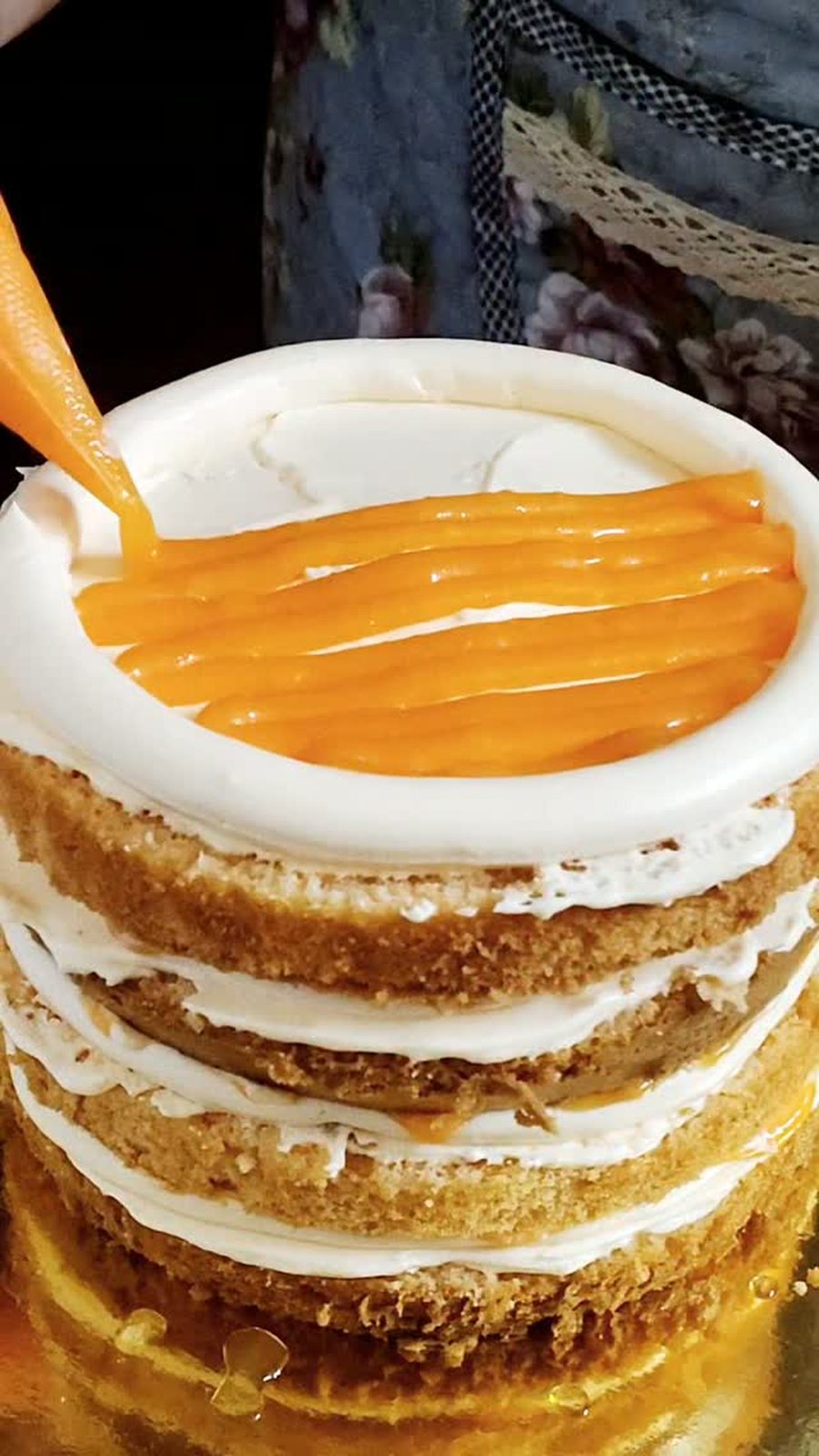 Orange curd being poured over a layer cake