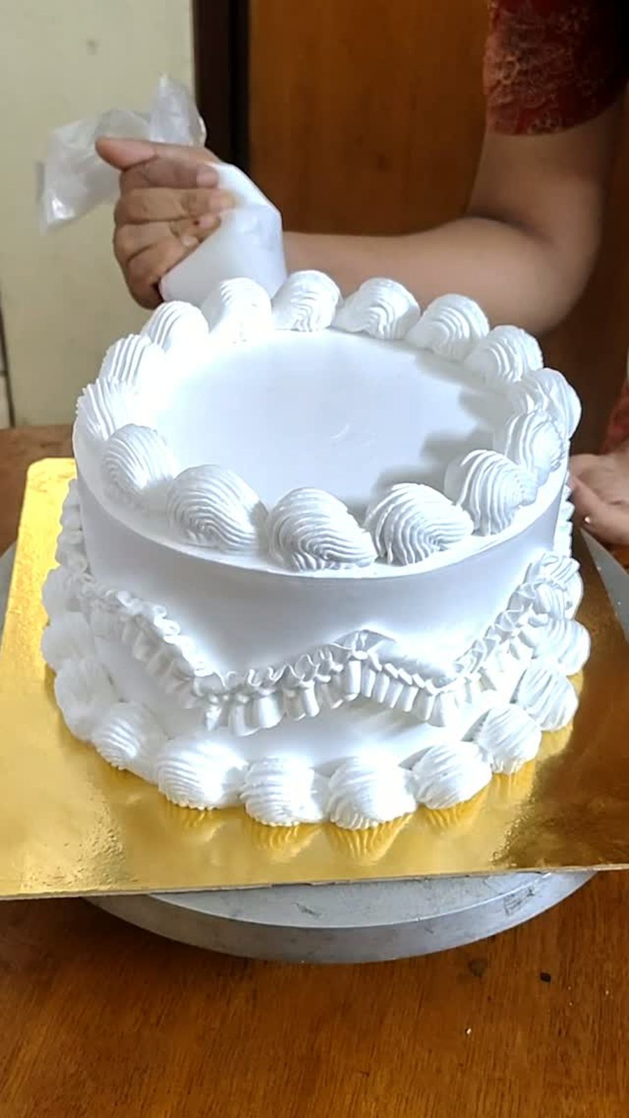 White ruffle cake being piped in the home kitchen