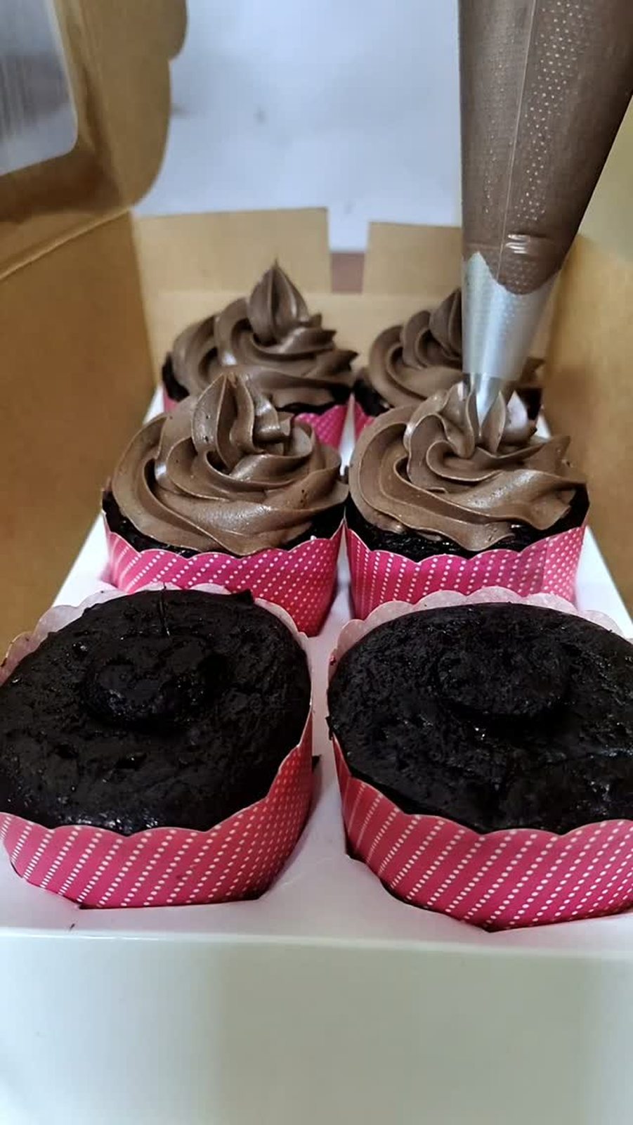 Chocolate cupcakes being frosted